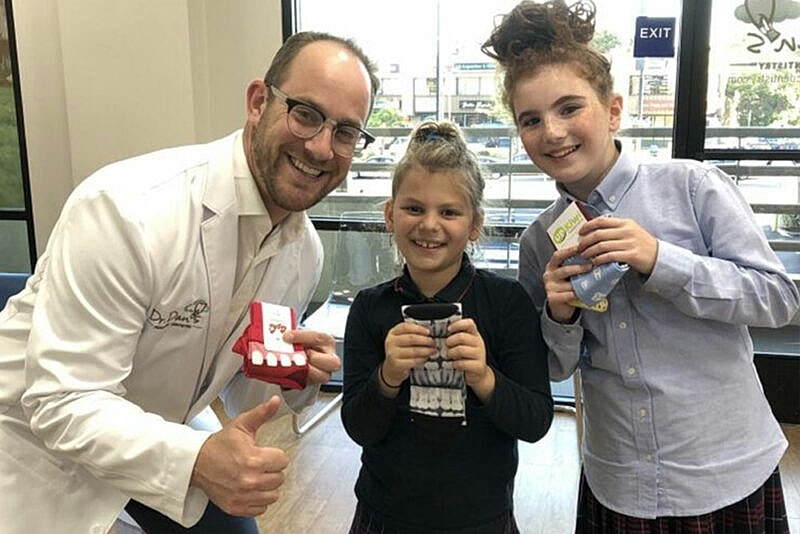 Smiling dentist with children holding prizes.