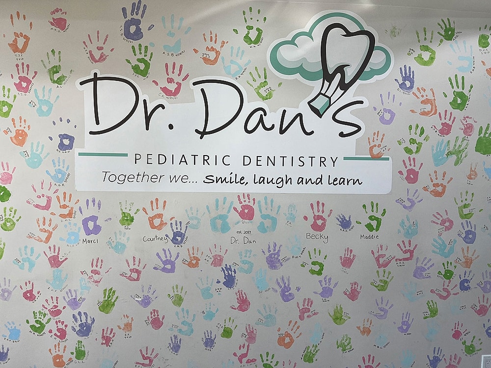 Colorful handprints on pediatric dentistry wall.